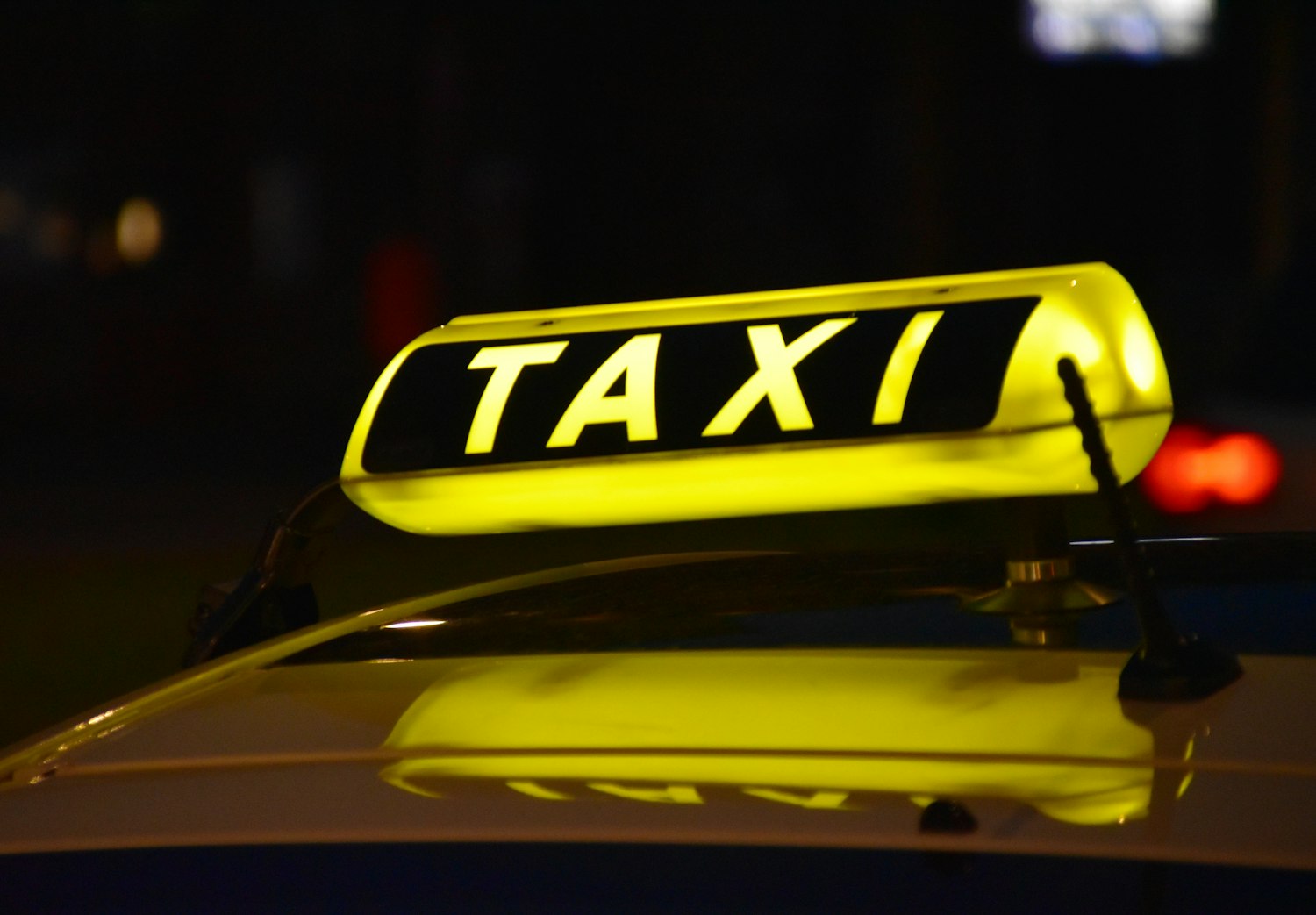 Verlichte taxi-daklamp op een wagen in de avond