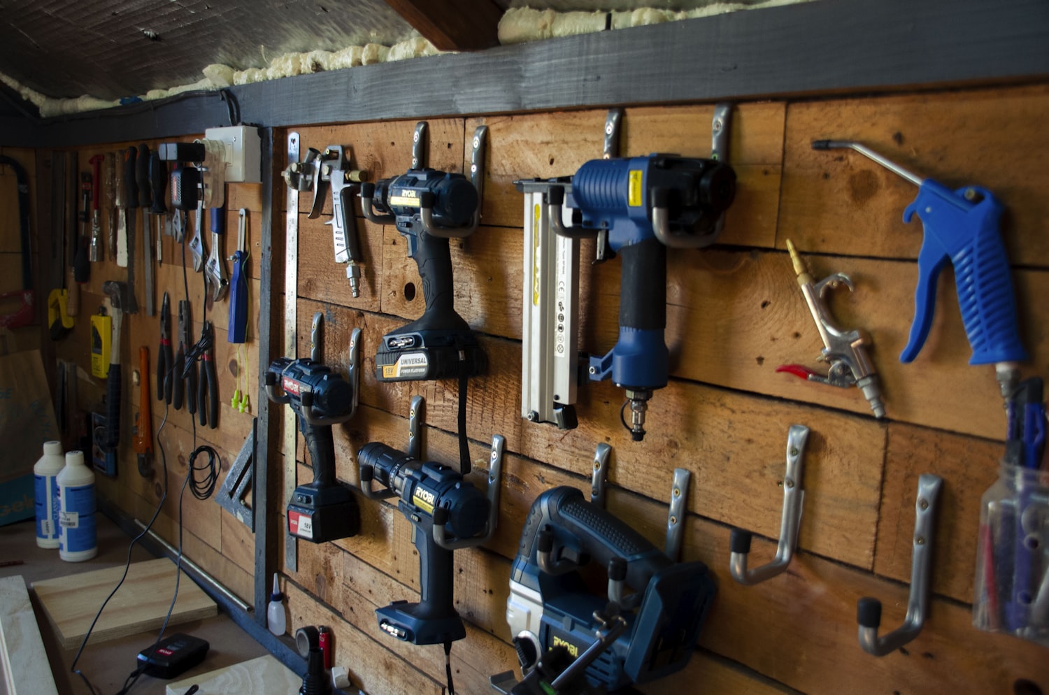 Muur met netjes opgehangen boormachines en handgereedschap in de werkplaats