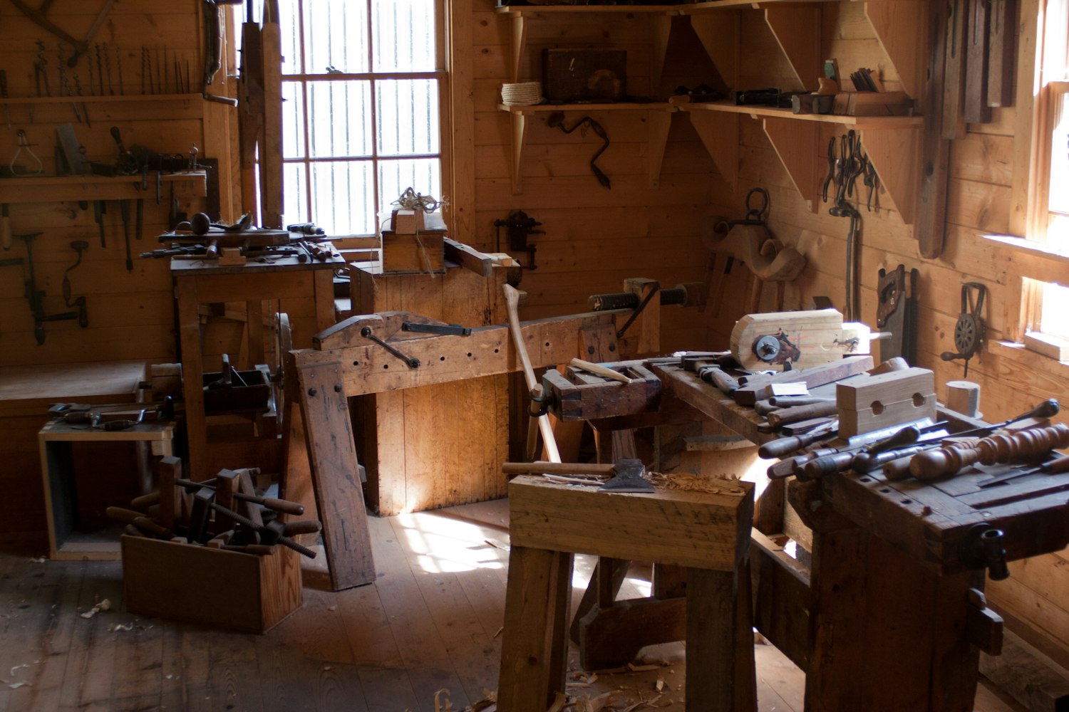 Houtbewerkingsatelier met werkbanken en handgereedschap aan de wand
